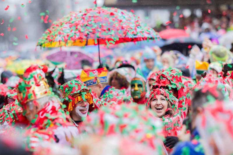 Carnival revelers are completely covered in wet confetti and celebrate the opening of the street carnival on Alter Markt on Weiberfastnacht (Women's Carnival Day). Rolf Vennenbernd/dpa