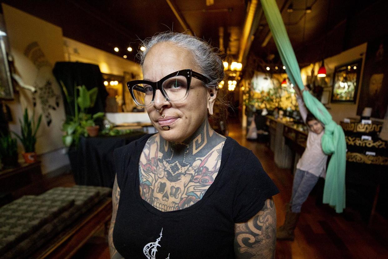 Alicia-Cardenas-owner-of-Sol-Tribe-Tattoo-and-Body-Piercing-stands-in-her-Broadway-shop-as-her-kid-Xochitl-plays-on-a-silk-behind-her-April-22-2020-Kevin-J.-Beaty-Denverite - Credit: Kevin J. Beaty/Denverite