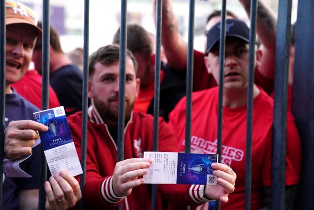 Liverpool fans stuck outside the stadium show their match tickets