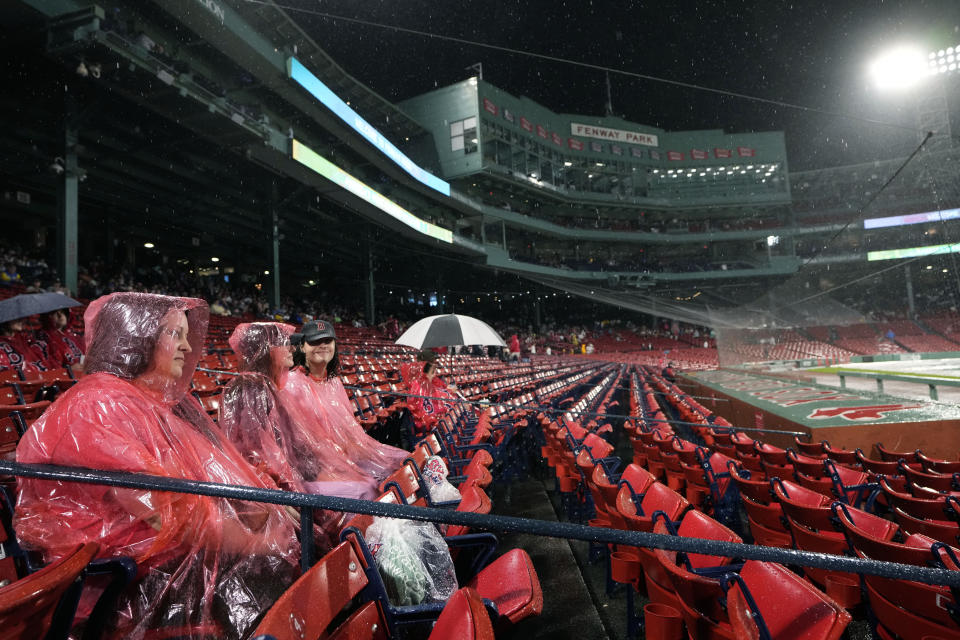 Baseball fans wear ponchos in the stands during a rain delay before a scheduled baseball game between the New York Yankees and the Boston Red Sox, Wednesday, Sept. 13, 2023, in Boston. (AP Photo/Steven Senne)