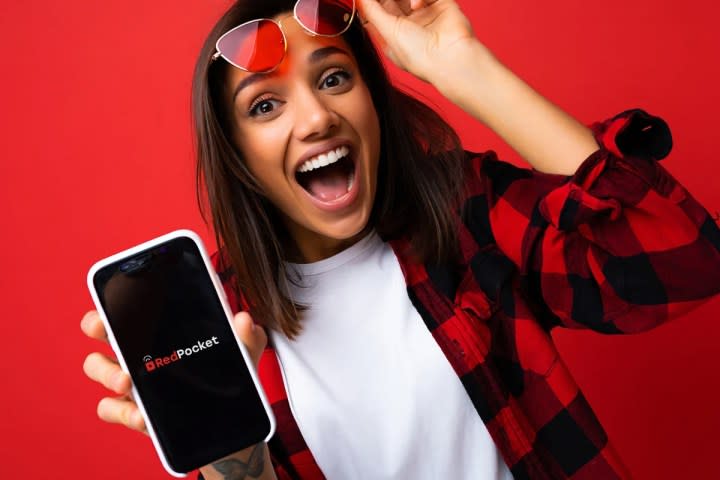 An excited woman holding up a smartphone with a Red Pocket Mobile logo.