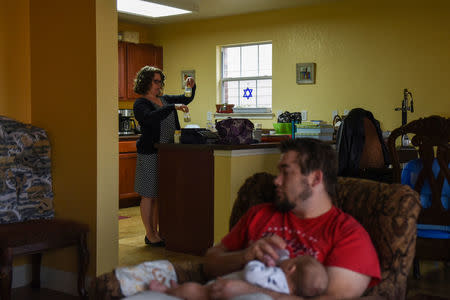 Lauren Hoffmann, 29, a college program manager, holds up the breast milk she pumped at work as her husband Will feeds Micah in San Antonio, Texas, U.S., February 13, 2019. REUTERS/Callaghan O'Hare