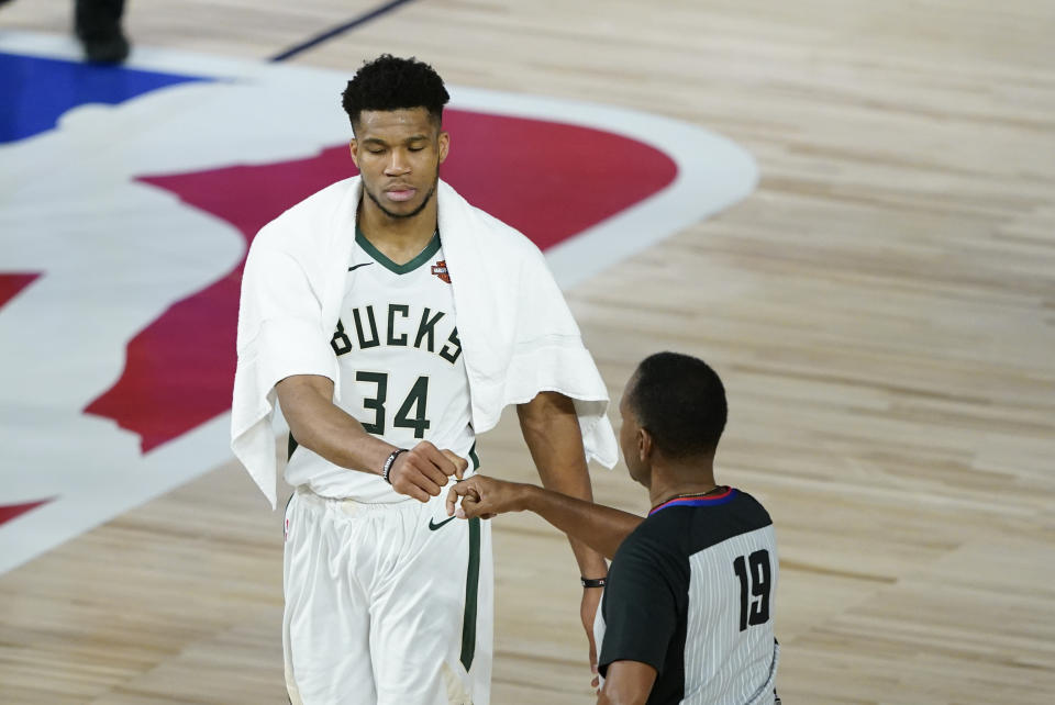 FILE - Milwaukee Bucks' Giannis Antetokounmpo (34) fist bumps referee James Capers (19) after an NBA basketball first-round playoff game against the Orlando Magic Monday, Aug. 24, 2020, in Lake Buena Vista, Fla. Safety is the primary reason why the status of the fist bump elevated big-time in 2020. The handshake was simply a causality of the coronavirus. (AP Photo/Ashley Landis, Pool, File)