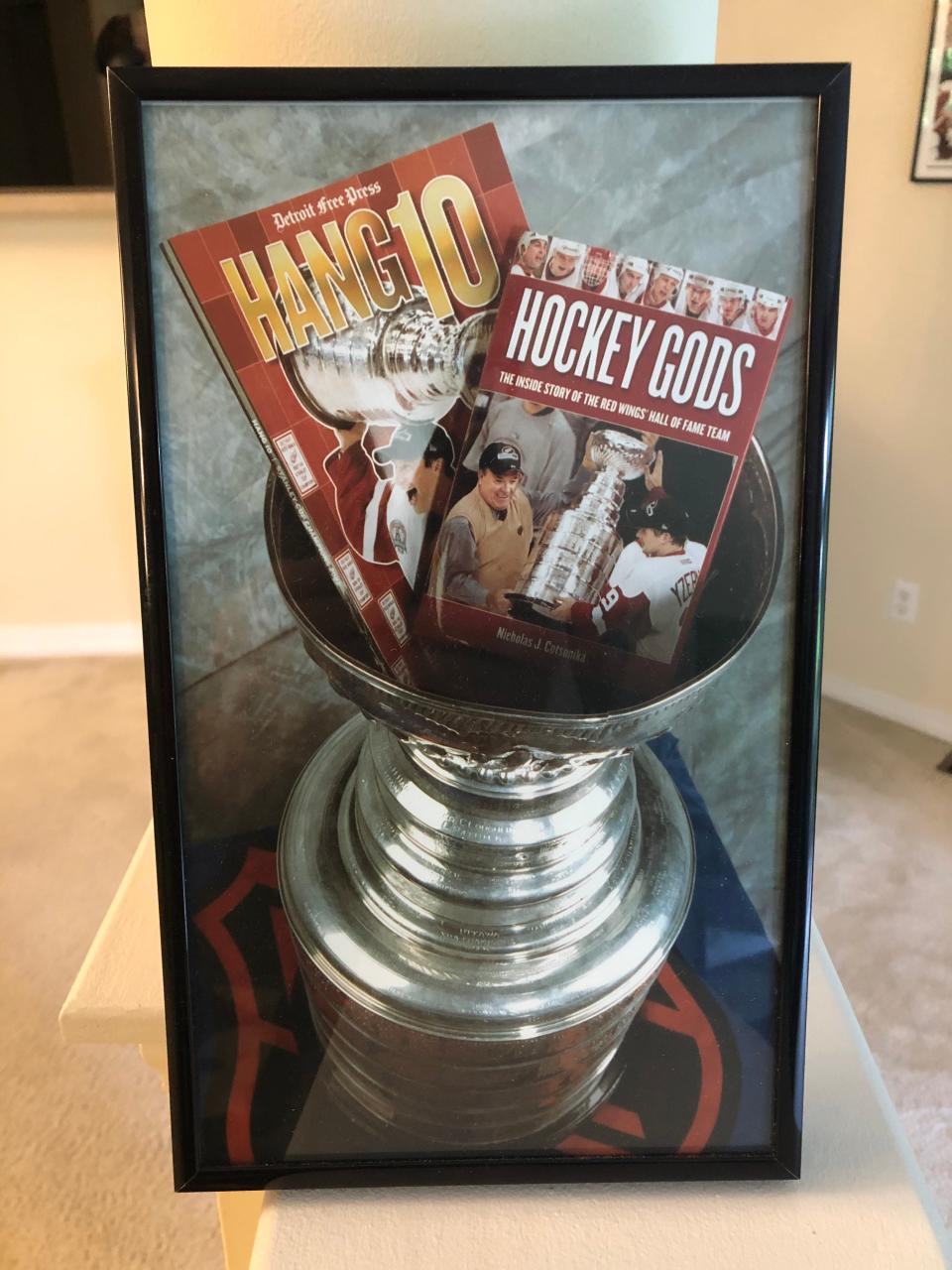 The Stanley Cup holding two Free Press Red Wings books commemorating the 2008 and 2002 championships.