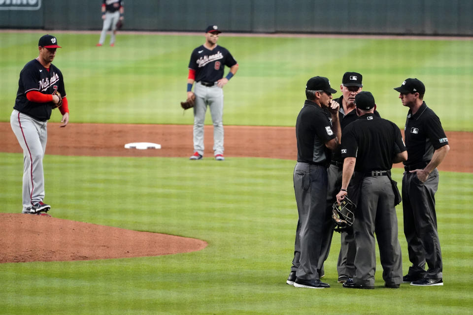 The umpiring crew meets before ejecting Washington Nationals pitcher Sean Nolin, left, after he hit Atlanta Braves' Freddie Freeman with aa pitch during the first inning of a baseball game Wednesday, Sept. 8, 2021, in Atlanta. (AP Photo/John Bazemore)