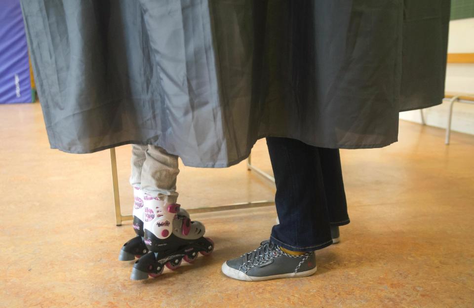 A father, right, stands with his child in a booth of a polling station, during the municipal elections in Paris, Sunday March 30, 2014. Voters in Paris and across France are going to the polls Sunday in municipal elections seen as a referendum on embattled President Francois Hollande's first two years in office. (AP Photo/Michel Euler)