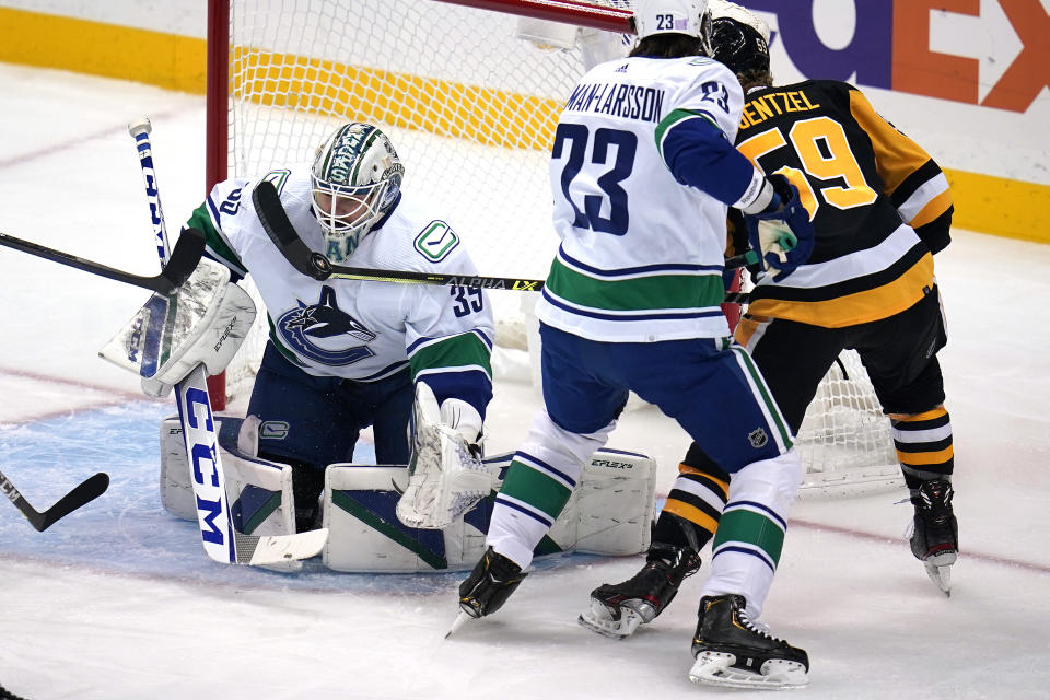 Pittsburgh Penguins' Jake Guentzel (59) can't get his stick on a rebound next to Vancouver Canucks goaltender Thatcher Demko (35) with Justin Dowling (73) defending during the first period of an NHL hockey game in Pittsburgh, Wednesday, Nov. 24, 2021. (AP Photo/Gene J. Puskar)