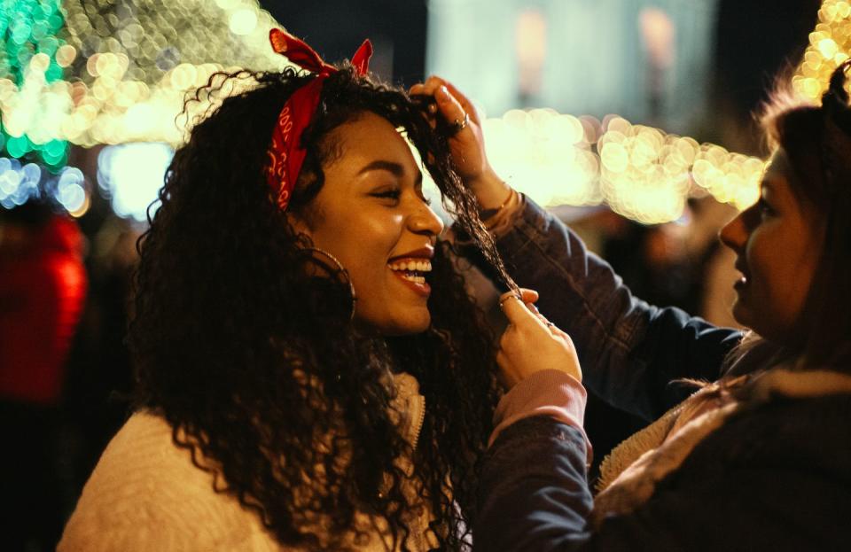 happy young woman standing with her girlfriend in city during christmas night