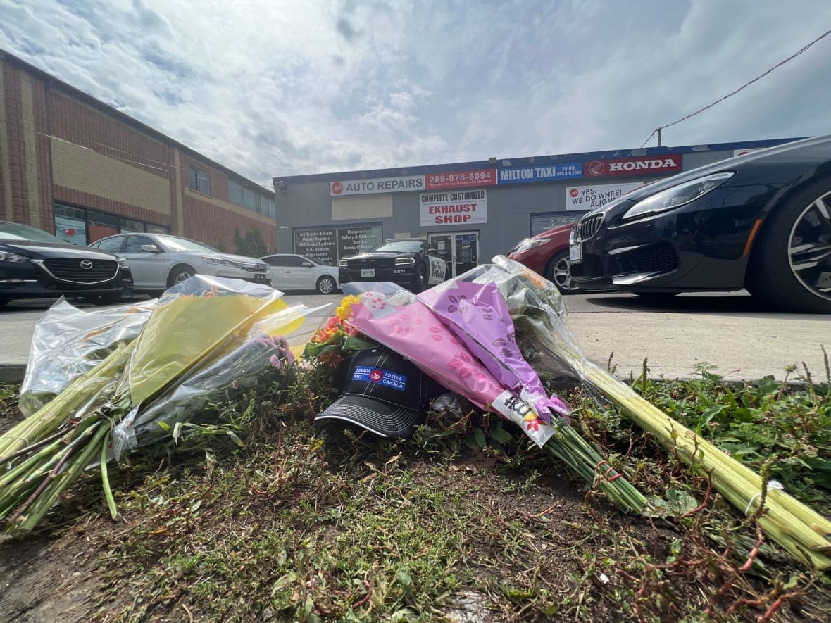 Flowers could be seen laid outside the Milton, Ont. auto body shop where owner Shakeel Ashraf was killed in Monday's shooting rampage. Police announced the death of a second victim, Satwinder Singh, 28, on Saturday. (Robert Krbavac/CBC - image credit)