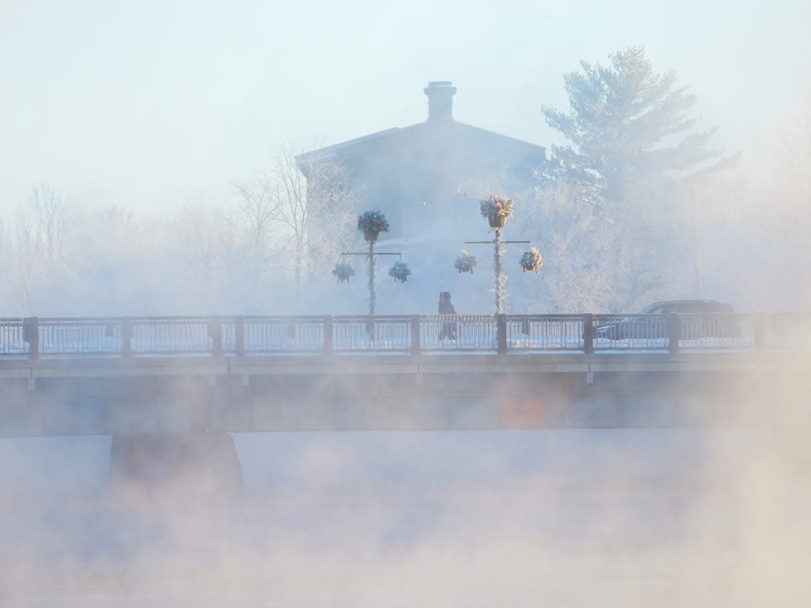 A pedestrian walks through the steam coming off the Mississippi River as temperatures hit -30 C in the Ottawa Valley in Carleton Place, Ont., on Jan. 21, 2022. (Sean Kilpatrick/The Canadian Press - image credit)