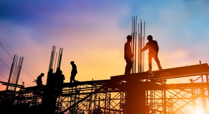 workers on a construction site with the sun setting in the background