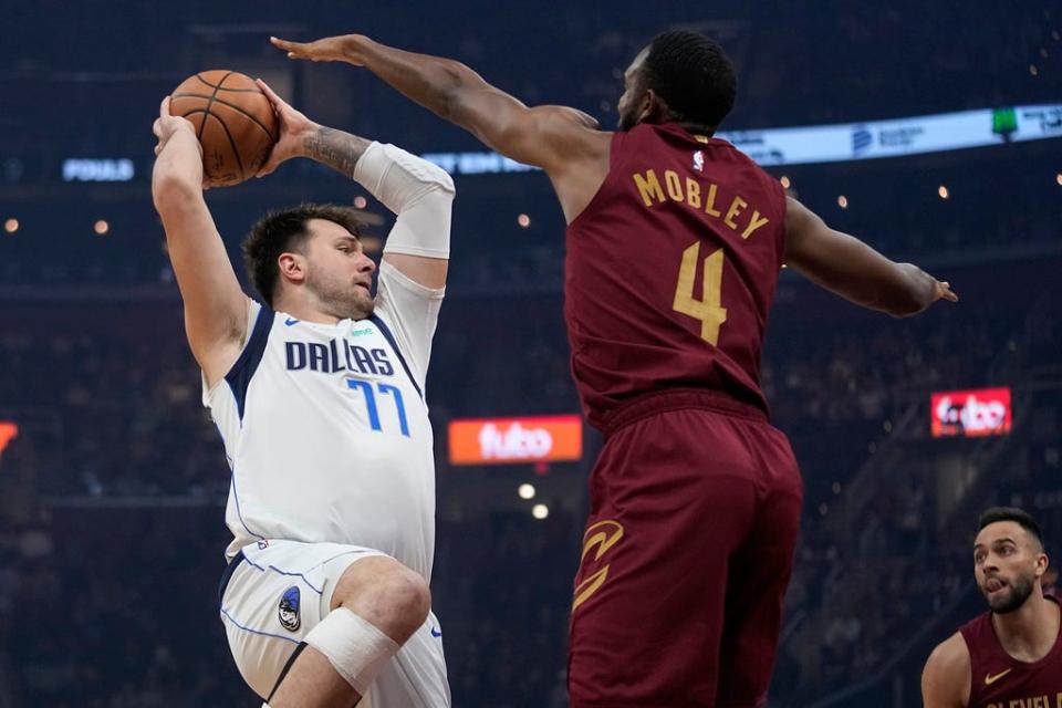 Dallas Mavericks guard Luka Doncic (77) passes under pressure from Cleveland Cavaliers' Evan Mobley (4) in the first half of an NBA basketball game, Tuesday, Feb. 27, 2024, in Cleveland. (AP Photo/Sue Ogrocki)