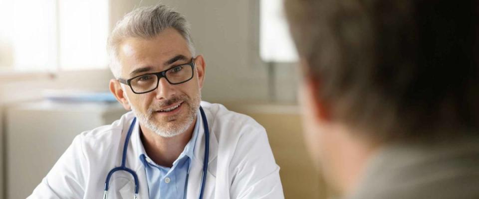 Doctor talking to patient in office, patient's back to the camera.