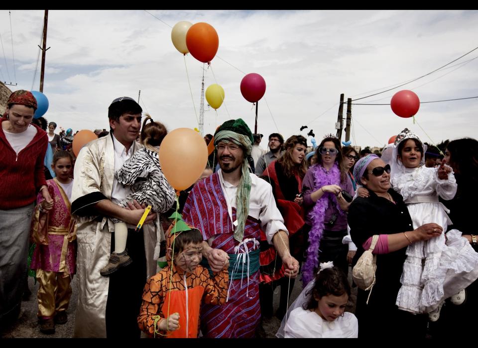 Israeli settlers and their children dressed in costumes hold balloons as they celebrate the annual Purim parade in the divided West Bank city of Hebron on March 20, 2011.