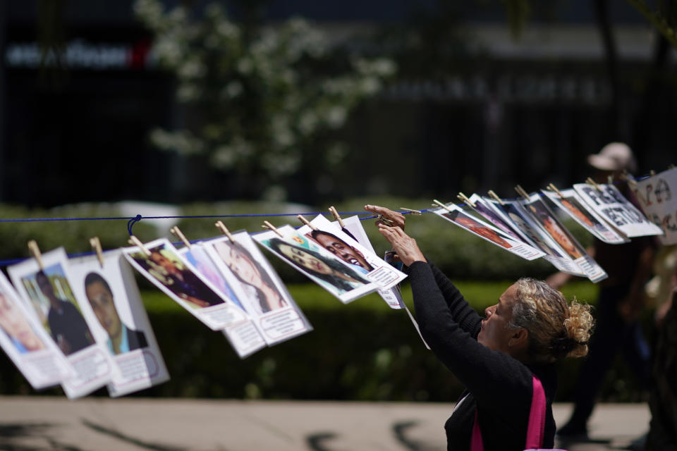 A woman hangs a portrait of a missing person on a makeshift line along Reforma Avenue during a march demanding the government do more to locate their loved ones, marking International Day of the Disappeared, in Mexico City, Wednesday, Aug. 30, 2023. Mothers of some of 111,000 people who have disappeared in Mexico over decades of violence, most believed to have been abducted by drug cartels or kidnapped by gangs, gathered on Wednesday on Reforma Avenue. (AP Photo/Eduardo Verdugo)