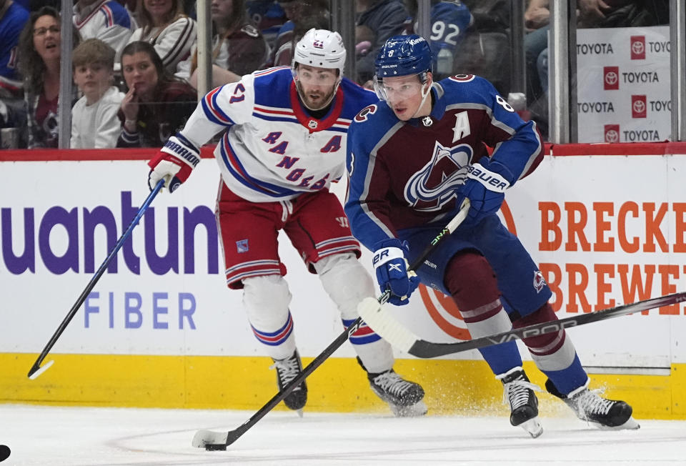 Colorado Avalanche defenseman Cale Makar, front, collects the puck as New York Rangers center Barclay Goodrow defends during the second period of an NHL hockey game Thursday, March 28, 2024, in Denver. (AP Photo/David Zalubowski)