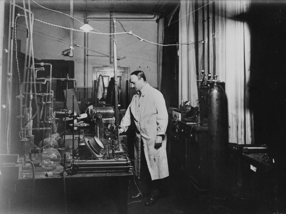 Nobel Prize winner James Franck stands wearing a white coat in his laboratory full of equipment circa 1925