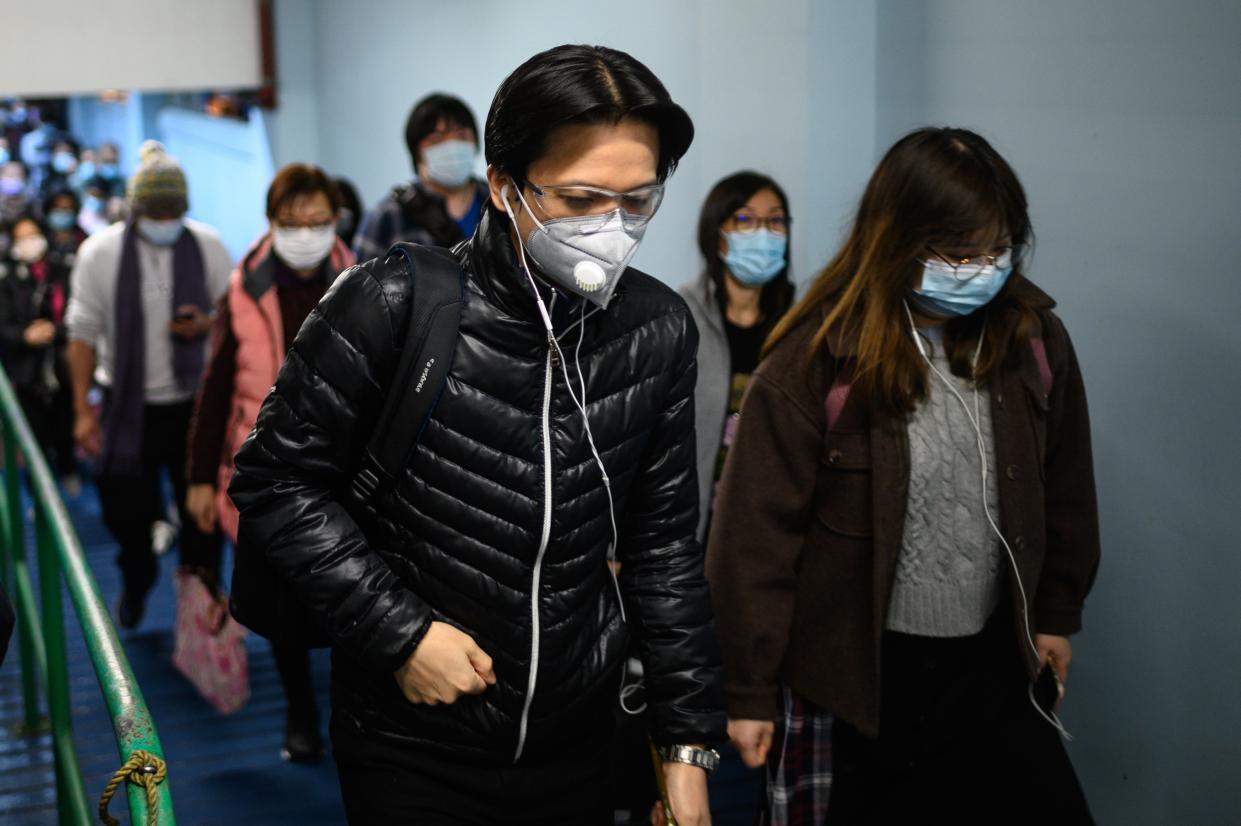 Passengers wearing face masks alight from a ferry in Hong Kong on February 5, 2020, as a preventative measure following a virus outbreak which began in the Chinese city of Wuhan. - More Chinese cities hunkered down by fencing off streets and telling millions of people to stay home as the death toll from the new coronavirus soared to nearly 500 on February 5. Hong Kong now has 18 confirmed infections, the majority people who were infected in mainland China. (Photo by Philip FONG / AFP) (Photo by PHILIP FONG/AFP via Getty Images)