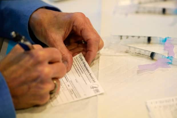 A health department worker in Pennsylvania fills out a vaccination record card before administering the Moderna COVID-19 vaccine to emergency medical workers and health-care personnel on Dec. 29, 2020. Nova Scotia's proof-of-vaccination policy comes into effect Monday, Oct. 4. (Matt Slocum/The Associated Press - image credit)