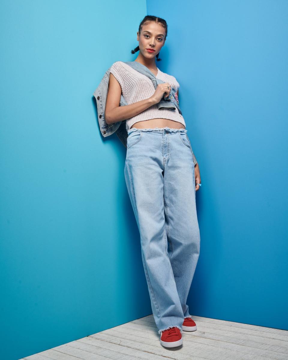 woman standing against blue wall in jeans and a crop top