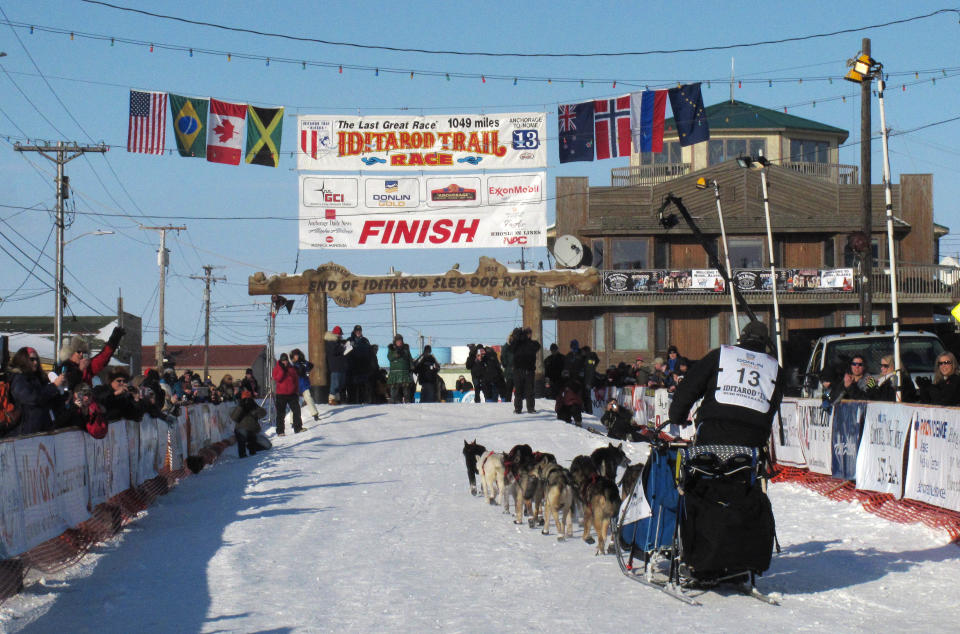 FILE - In this March 13, 2013, file photo, residents greet Kotzebue musher John Baker as he nears the finish line in Nome, Alaska. If you want to see mushers cross the finish line at the world's most famous sled dog race in March 2014, better make your reservations soon. There aren’t many hotel rooms available at the end of the Iditarod Trail Sled Dog Race in Nome, leaving mushers and their families battling with fans, tourists and volunteers for a place to sleep. (AP Photo/Mark Thiessen, file)