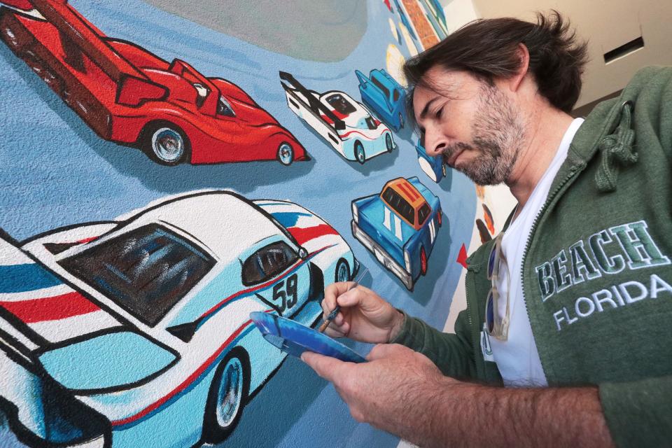 Artist Erwin Dazelle works on a racing themed mural, Tuesday November 16, 2021 on a wall of the Dayona Hotel at One Daytona.