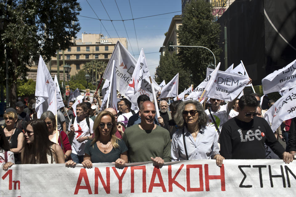 Greek Former Finance Minister Yanis Varoufakis, center, and his wife Danae Stratou second left, hold a banner which reads on Greek Disobedience, as they take part in a rally with other protesters in central Athens, on Wednesday, May 1, 2019. Thousands people gathered in central Athens Wednesday for three separate rallies and marches to parliament organized by unions and left-wing groups. Greece has been left without national rail, island ferry and other transport services for a day as unions hold strikes and rallies to celebrate May Day.(AP Photo/Petros Giannakouris)