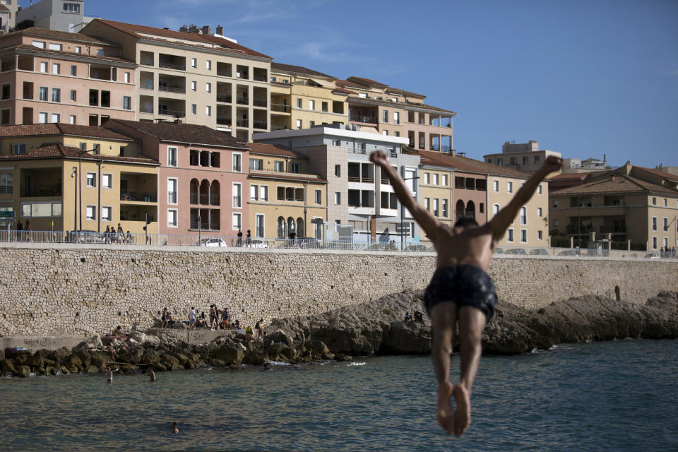 FILE - In this July 25, 2020, file photo, a boy jumps into the sea at the Plage des Catalans in Marseille, southern France. An outbreak among 18- to 25-year-olds at a seaside resort on the Brittany coast is crystallizing fears that the virus is flaring again in France, on the back of vacationers throwing COVID-19 caution to the summer winds. (AP Photo/Daniel Cole, File)