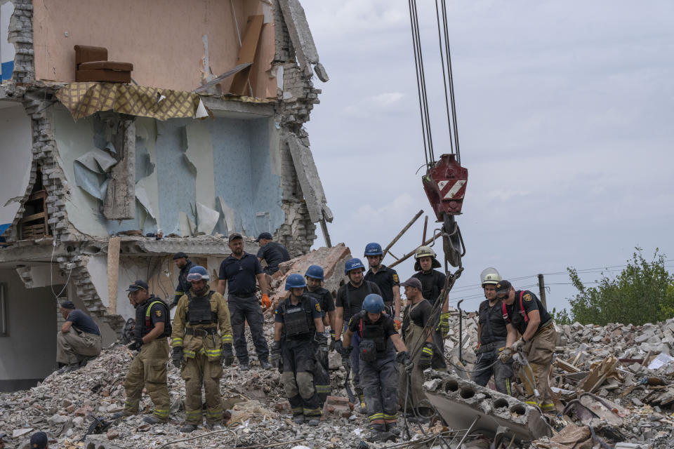 Rescue workers sift through rubble at the scene in the after math of a Russian rocket that hit an apartment residential block, in Chasiv Yar, Donetsk region, eastern Ukraine, Sunday, July 10, 2022. At least 15 people were killed and more than 20 people may still be trapped in the rubble, officials said Sunday. (AP Photo/Nariman El-Mofty)