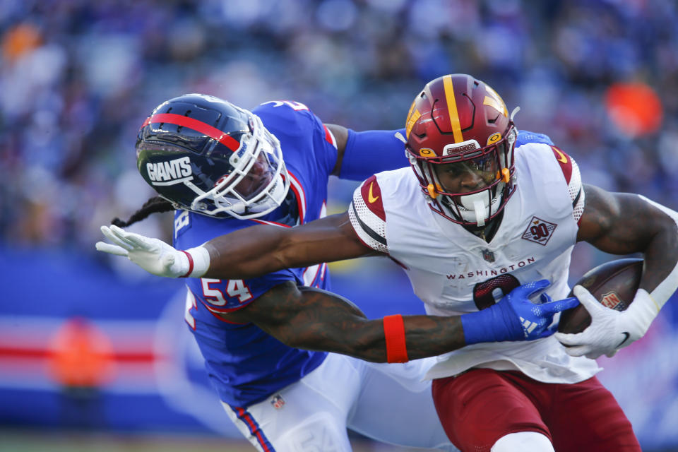 Washington Commanders' Brian Robinson Jr., right, runs past New York Giants' Jaylon Smith during the first half of an NFL football game, Sunday, Dec. 4, 2022, in East Rutherford, N.J. (AP Photo/John Munson)