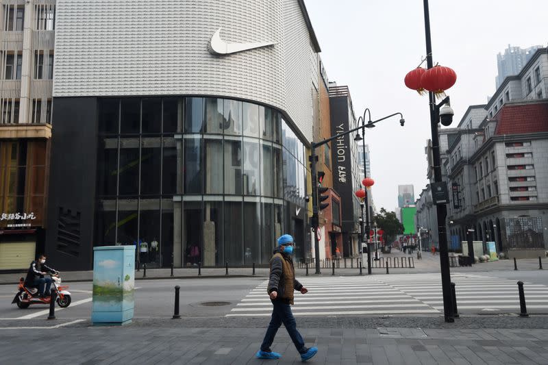 Man wearing protective gear walks past a Nike store at a main commercial area in Wuhan, the epicentre of the novel coronavirus outbreak