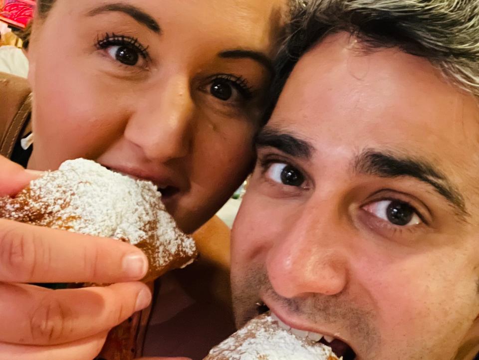 carly and her husband eating beignets in downtown disney