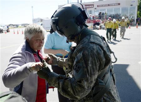 SFC Keith Bart (R) helps a woman who was winched up to a helicopter flown by members of 2-4 GSAB 4th Infantry Division based in Ft. Carson, near Jamestown, Colorado September 17, 2013. REUTERS/Mark Leffingwell