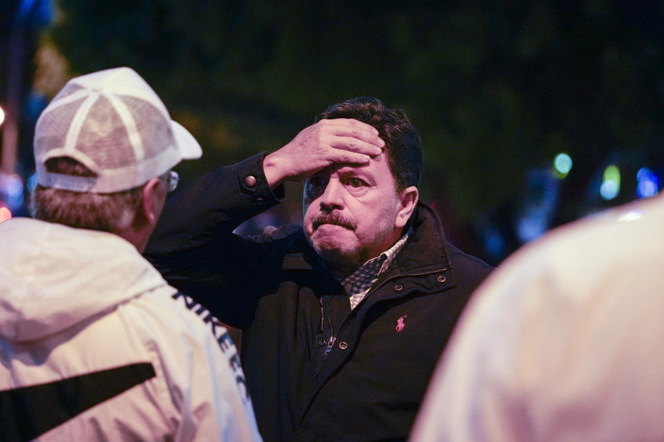 A man puts his hand on his forehead after presidential candidate Fernando Villavicencio was shot to death as he left a campaign rally, outside a school in Quito, Ecuador, Wednesday, Aug. 9, 2023. (API via AP)