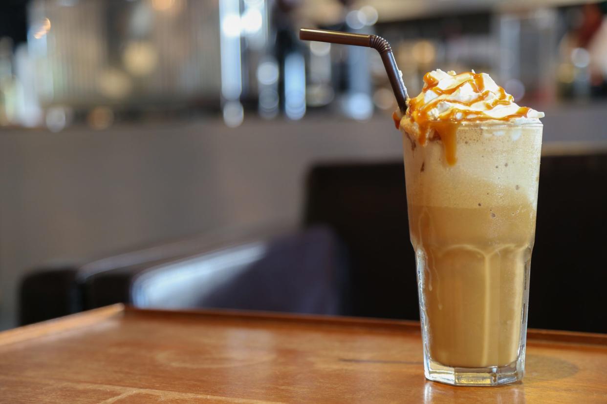 Caramel frappe coffee on brown wood table with space in the coffee shop.