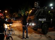 A demonstrator forms a heart shape with his hands in front of a police vehicle during a protest at the National University as a national strike continues in Bogota