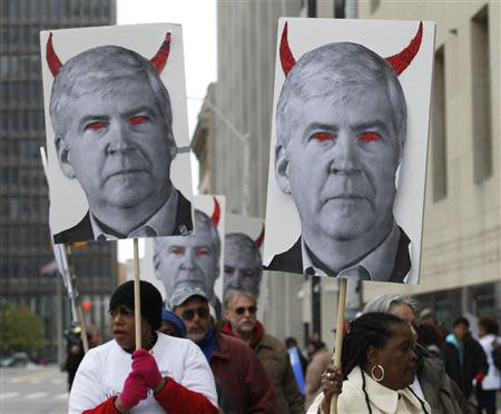 Protesters hold posters depicting Michigan Governor Rick Snyder as a devil, during a protest against cuts in city workers' pensions and the filing of the Municipal Bankruptcy, in front of the Federal Court House in Detroit, Michigan October 28, 2013. REUTERS/Rebecca Cook