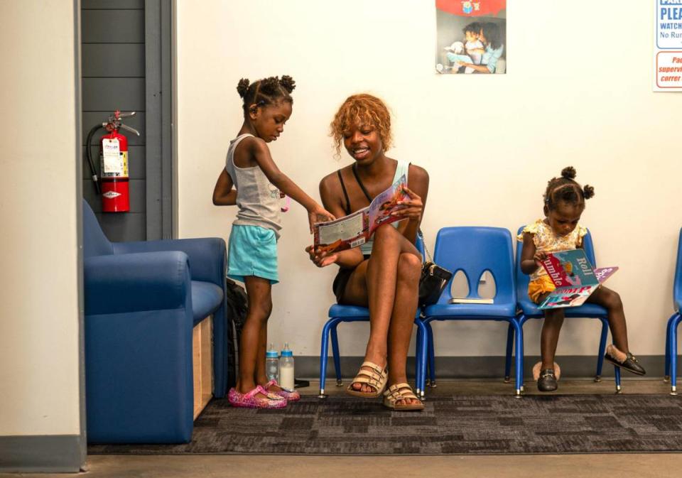 Cheriah Seawood, left, Anotida Mafuvadze, and Chenel Seawood, read books together in the children’s corner at Leah’s Laundromat. Community Laundry Day is staffed by a network of volunteers, health care workers, and community advocates who assist in providing help and social services to customers.