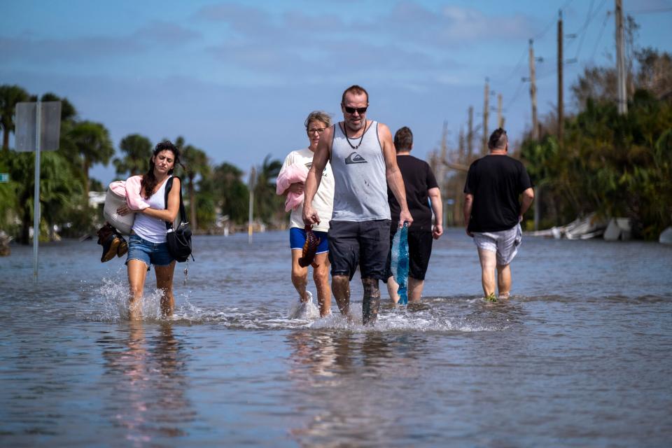 People wade through floodwaters in the aftermath of Hurricane Ian in Fort Myers, Fla., on Sept. 29.