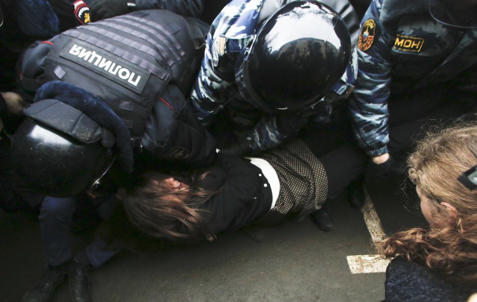 Russian police officers detain member of the Pussy Riot punk group, Nadezhda Tolokonnikova, center, as the other member Maria Alekhina looks on from right outside a court room in Moscow, Russia, Monday, Feb. 24, 2014, where hearings started against opposition activists detained on May 6, 2012 during a rally at Bolotnaya Square. A Moscow judge on Friday, Feb. 21, 2014, convicted eight anti-government protesters of rioting during a 2012 protest against Vladimir Putin, following a trial seen as part of the Kremlin's efforts to stifle dissent. (AP Photo/Denis Tyrin)