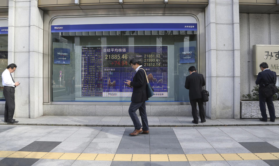 People look at their cell-phone in front of an electronic stock board of a securities firm in Tokyo, Wednesday, Nov. 14, 2018. Asian shares were mostly lower Wednesday, after the steepest drop in oil prices in more than three years put investors in a selling mood on Wall Street.(AP Photo/Koji Sasahara)