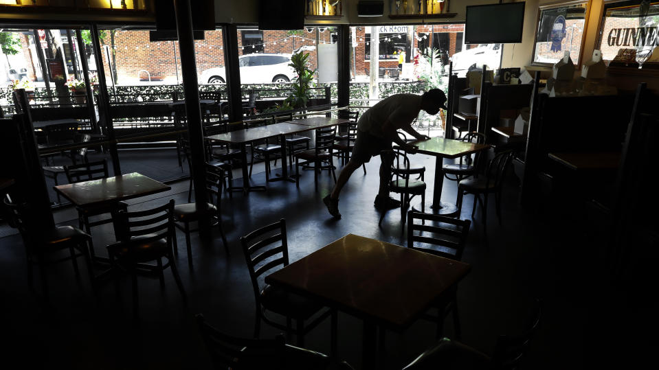 FILE - In this June 8, 2020, file photo, co-owner Justin Herrick arranges tables at Good Time Charley's in Ann Arbor, Mich. As more and more schools and businesses around the country get the OK to reopen, some college towns are moving in the opposite direction because of too much partying and too many COVID-19 infections among students. (AP Photo/Paul Sancya, File)