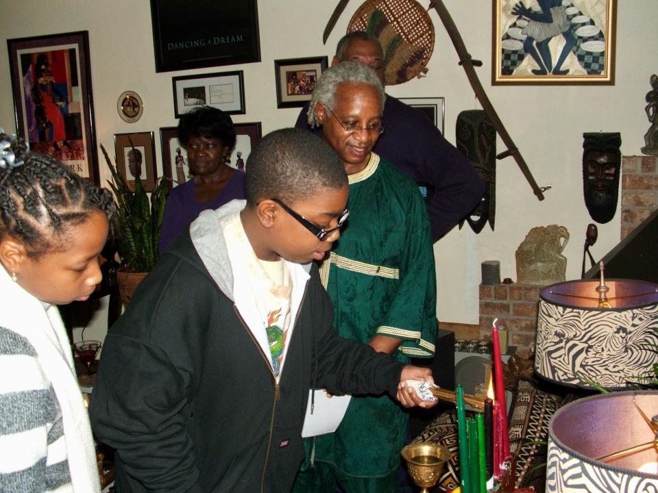 Kwame T. Mumina's young family members help light Kwanzaa candles.