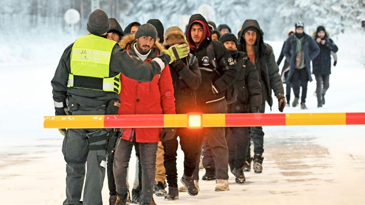  A line of migrants waits to speak with a guard at a border crossing in Finland. 