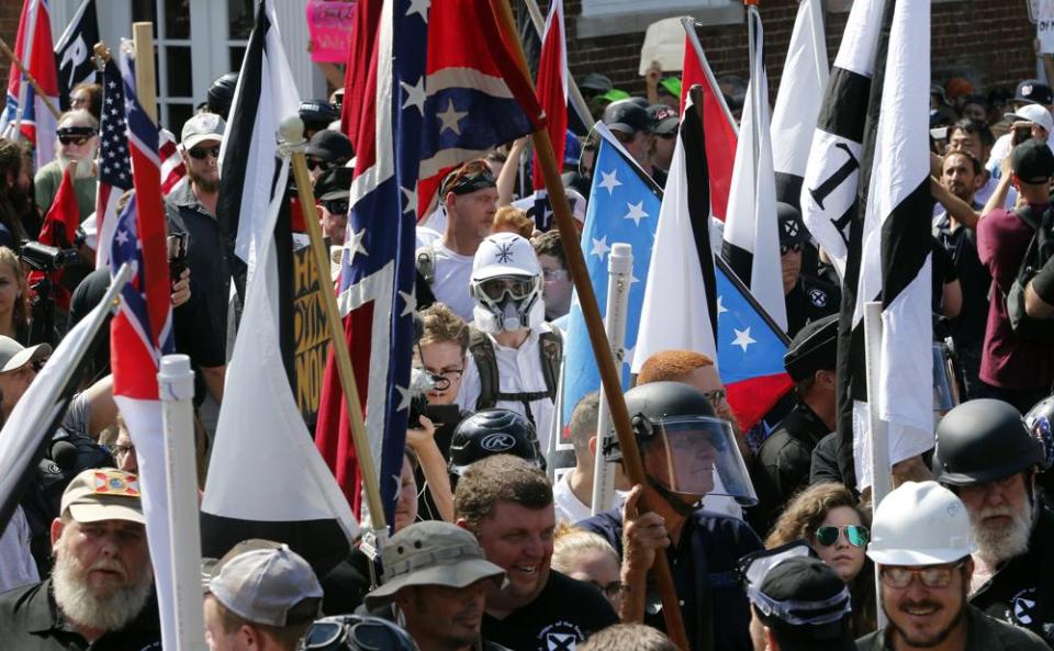 White nationalist demonstrators walk into the entrance of Lee Park surrounded by counter demonstrators in Charlottesville, Va., Saturday, Aug. 12, 2017. (AP Photo/Steve Helber)