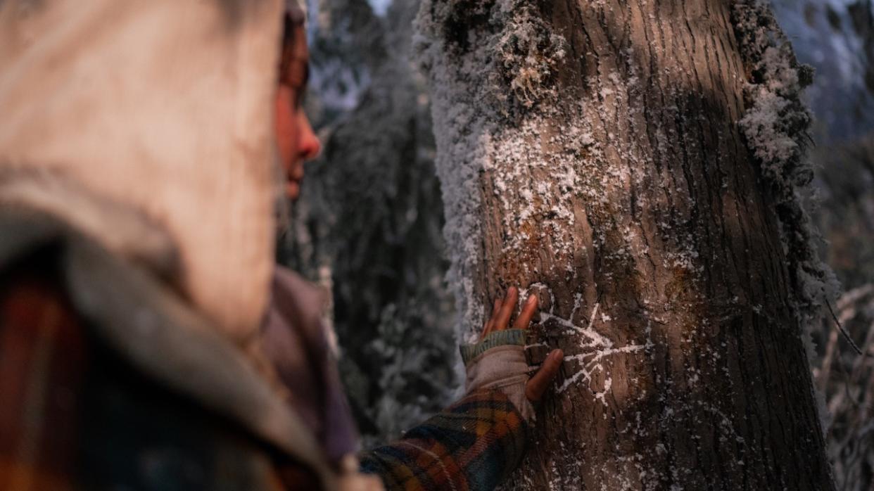  Lottie touching symbol on snowy tree in Yellowjackets 