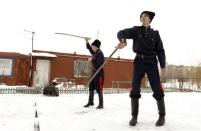 Russian Cossacks Vitaly Timoshenko (R), 19, and Vyacheslav Timoshenko, 13, juggle swords in the town of Krasny Oktyabr, on the outskirts of the southern Russian city of Volgograd, January 5, 2014. REUTERS/Vasily Fedosenko