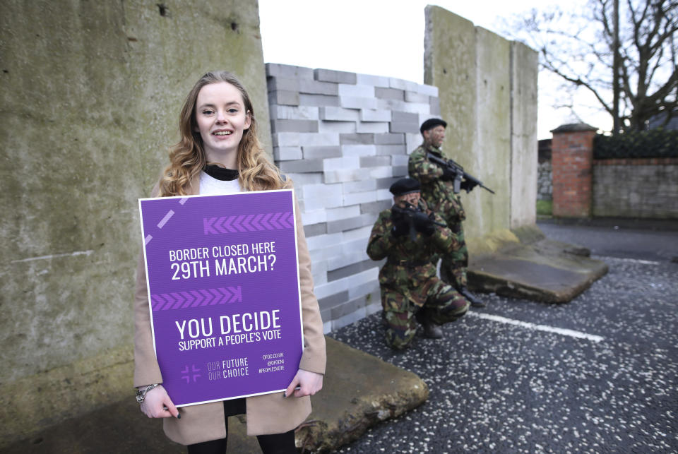 A demonstrator holds a banner on the Northern Ireland/Republic of Ireland border, near Newry in Northern Ireland, Saturday, Jan. 26, 2019. Protesters angered at the prospect of a hard Brexit built a mock wall across part of the Irish border, the theatrical gesture on Saturday was the centrepiece of a County Down demonstration against future border checks. (AP Photo/Peter Morrison)