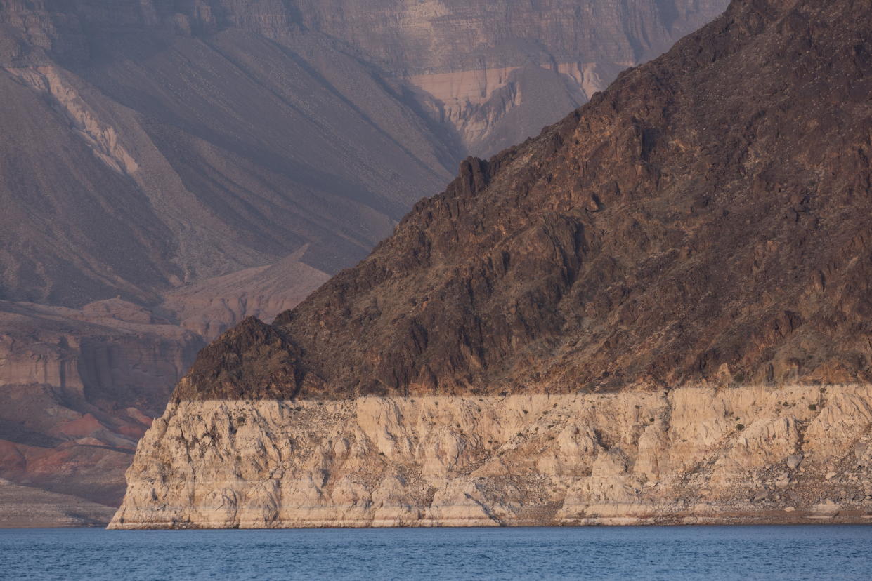 A thick white ring above the coastline of a lake, and below a darker mountainous terrain, shows the dramatic decline of water levels at Lake Mead.