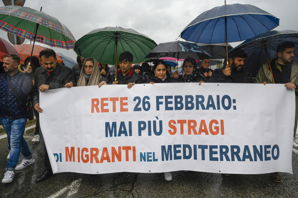 Survivors and family members of the victims march in Crotone, southern Italy, Sunday, Feb. 25, 2024, to help mark the first anniversary of the shipwreck of a migrant boat that capsized in the early morning of Sunday, Feb. 26, 2023, at a short distance from the shore in Steccato di Cutro, near Crotone, killing at least 94 people. Survivors and family members of the victims are converging in the area for a commemoration on Monday, Feb. 26, 2024, on the first anniversary of the disaster. The banner in Italian reads: "February 26 Network: never again migrants slaughter in the Mediterranean Sea". (AP Photo/Valeria Ferraro)